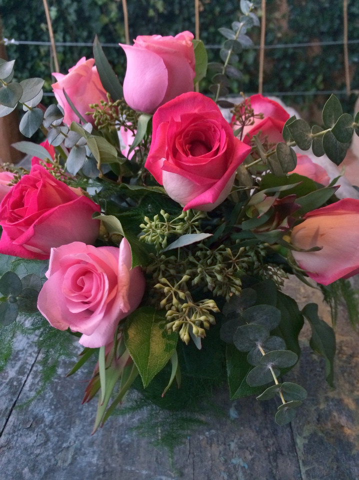 One dozen roses and greens with accents in a clear glass cube